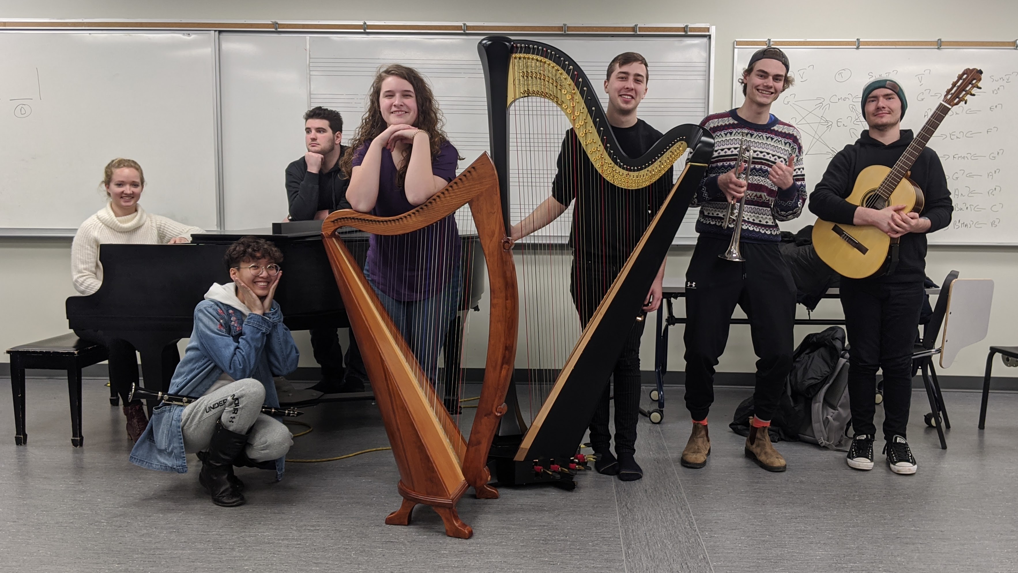 A group photo of the ensemble members of FIRE posing with their instruments in a classroom